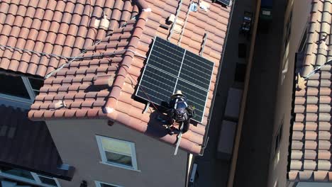 static drone shot of installer on home roof, working on new solar panels, clean energy