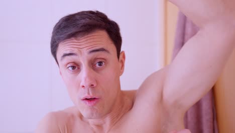handsome man applying deodorant in bathroom mirror