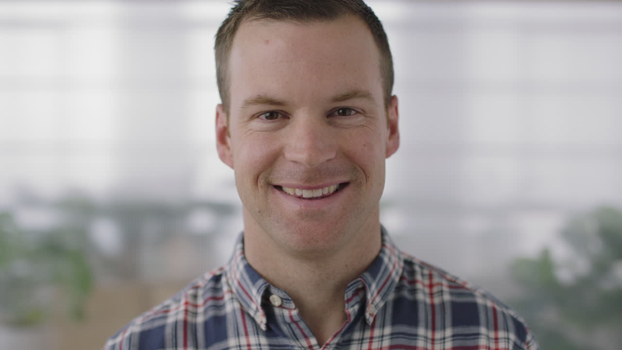 close up portrait of handsome young businessman entrepreneur smiling happy looking at camera confident caucasian male in workplace