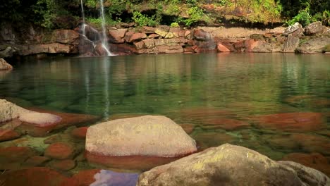 waterfall streams falling form rock with calm water reflection from flat angle