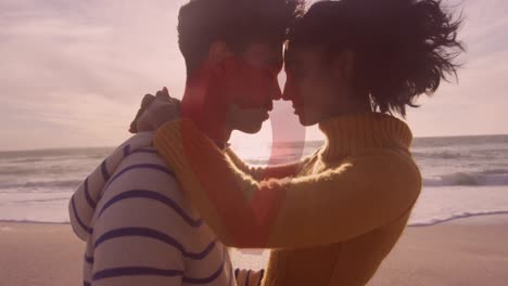 animation of red heart over couple in love embracing on beach