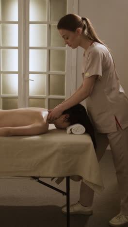 a woman receiving a neck and shoulder massage from a professional masseuse at a spa