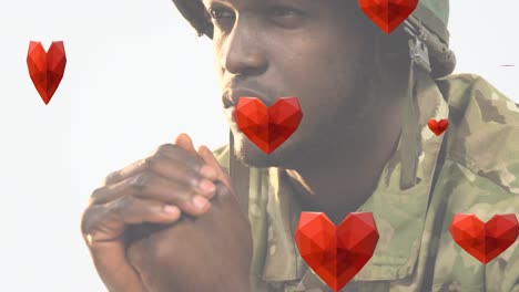 animation of hearts falling over african american male soldier praying