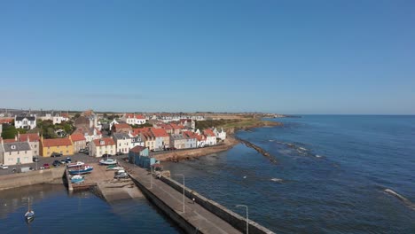 Aerial-sweep-from-st-Monance-harbour-around-the-coastline-with-a-boat-passing-by