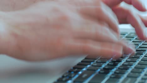 close-up of male hands typing text on a laptop keyboard