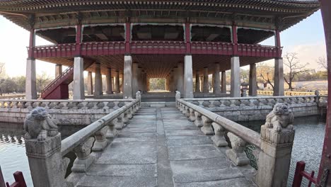 gyeonghoeru pavilion at gyeongbokgung palace in seoul - elevated banquet hall on artificial pond viewed through open wooden gates. pov shot