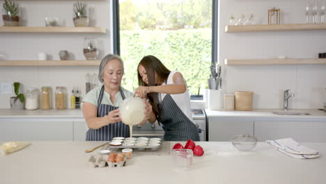 baking cupcakes, asian grandmother and granddaughter pouring batter into tray in kitchen