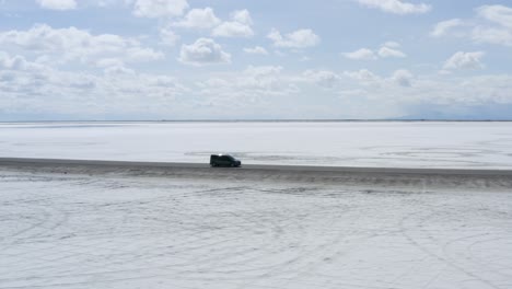 Car-Driving-Fast-on-Salt-Flat-Desert-Road---Aerial-Establisher