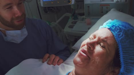 close-up of caucasian man comforting pregnant woman during labor in operation theater