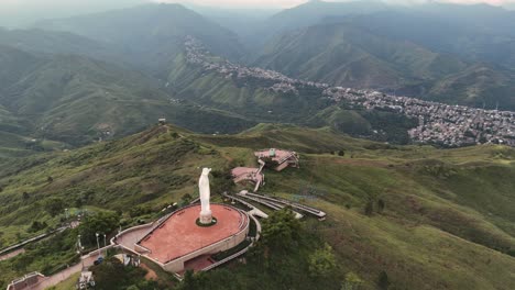 aerial view of a large statue on a mountain overlooking a town