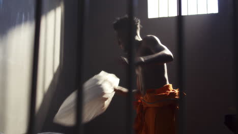 frustrated inmate screaming in pillow and throwing it on prison bed