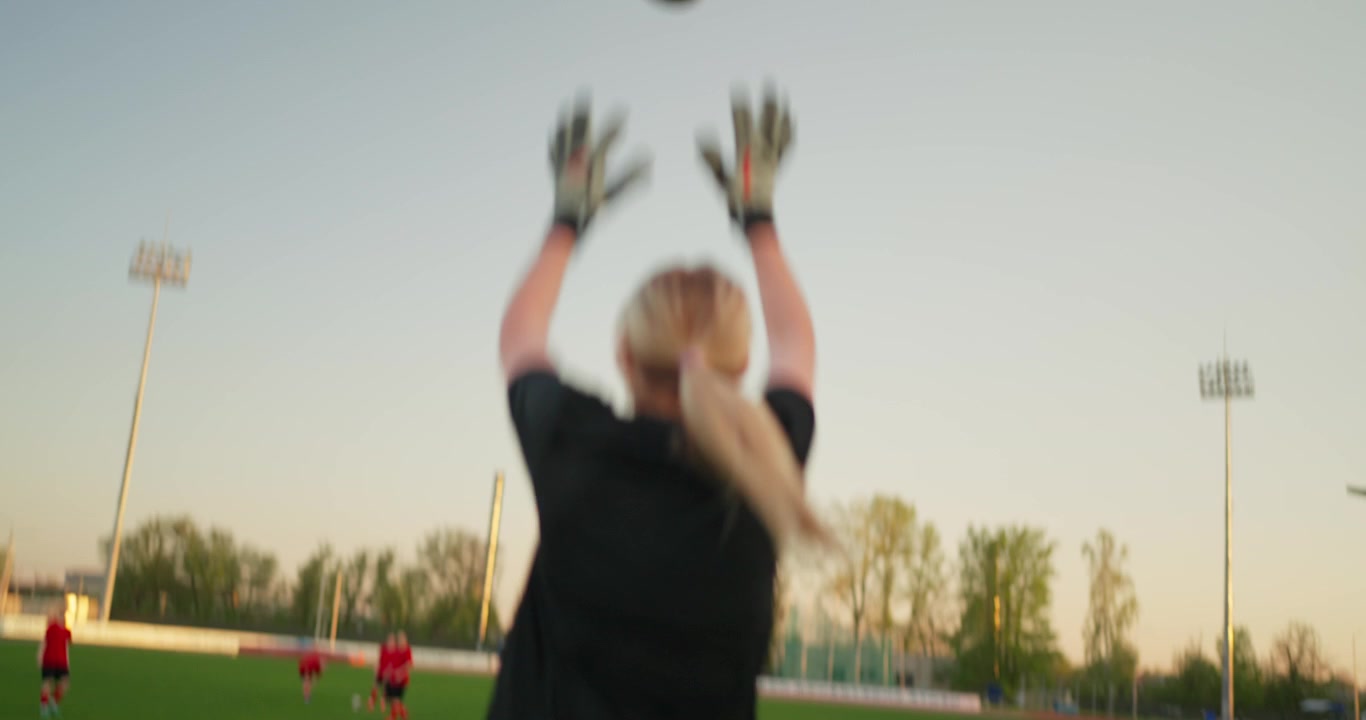 Female Goalkeeper Catches Soccer Ball and Warms Up on Green Field