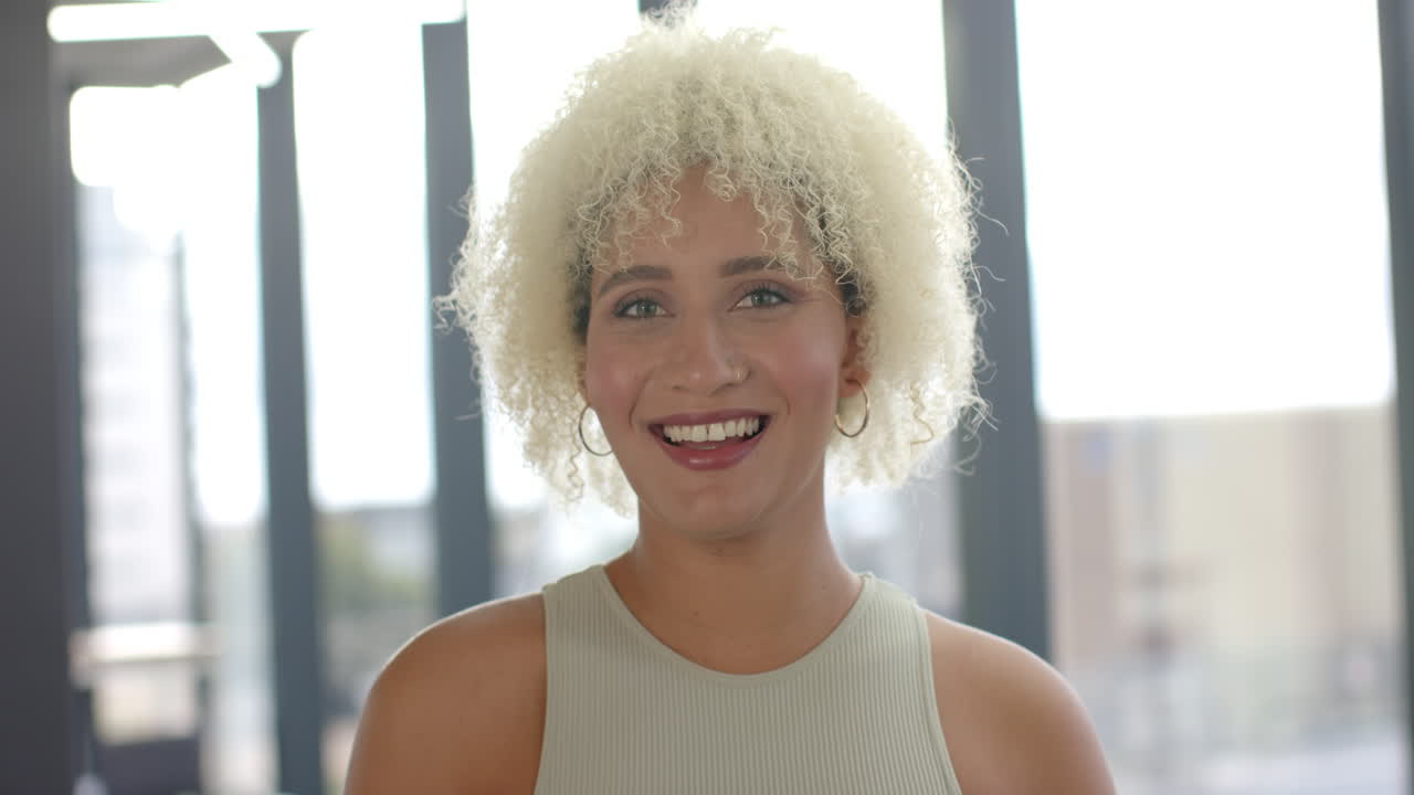 Smiling woman with curly hair posing in bright office environment