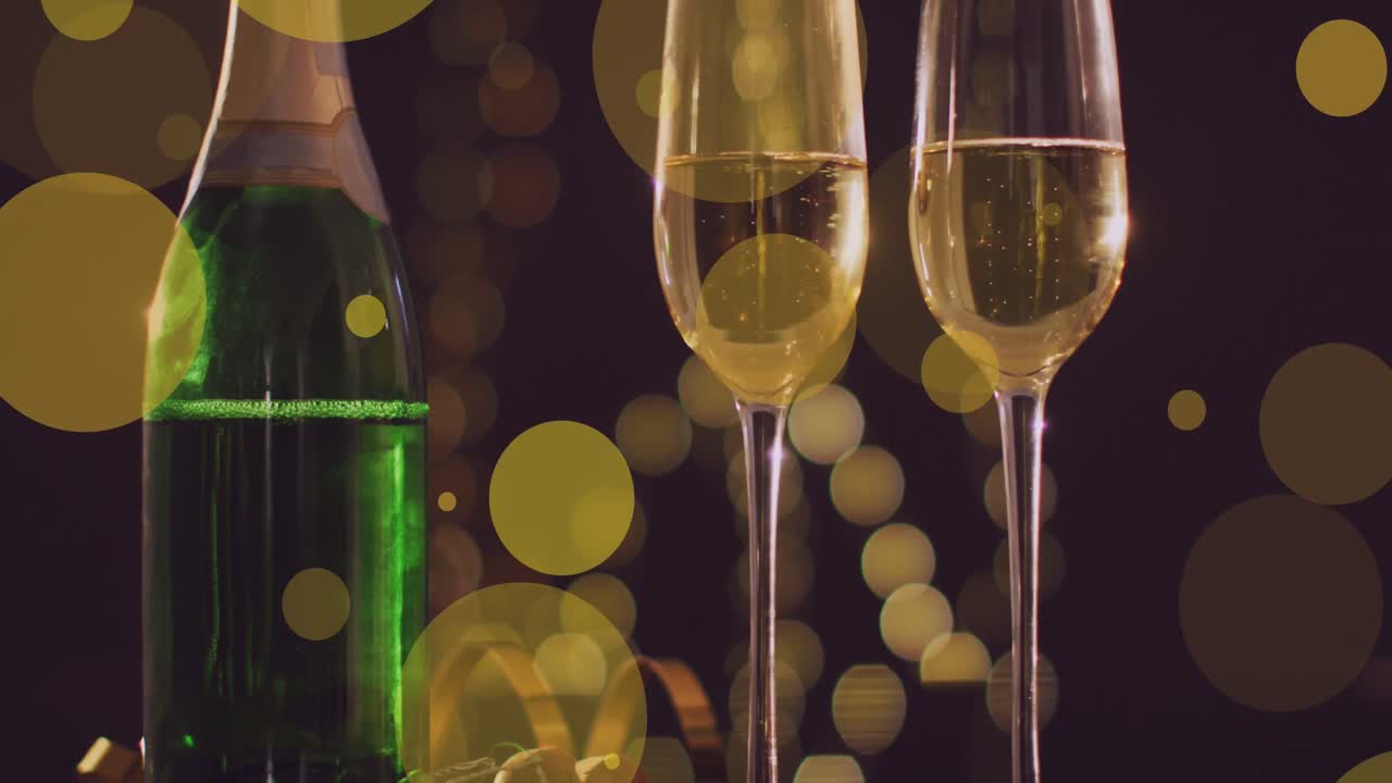 Animazione di punti di luce gialli su due calici e una bottiglia di champagne di Capodanno.