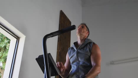 Fit-sweaty-caucasian-man-exercising-on-training-bike-inside-gym