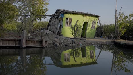 a poor little green house barely stands tall by the river