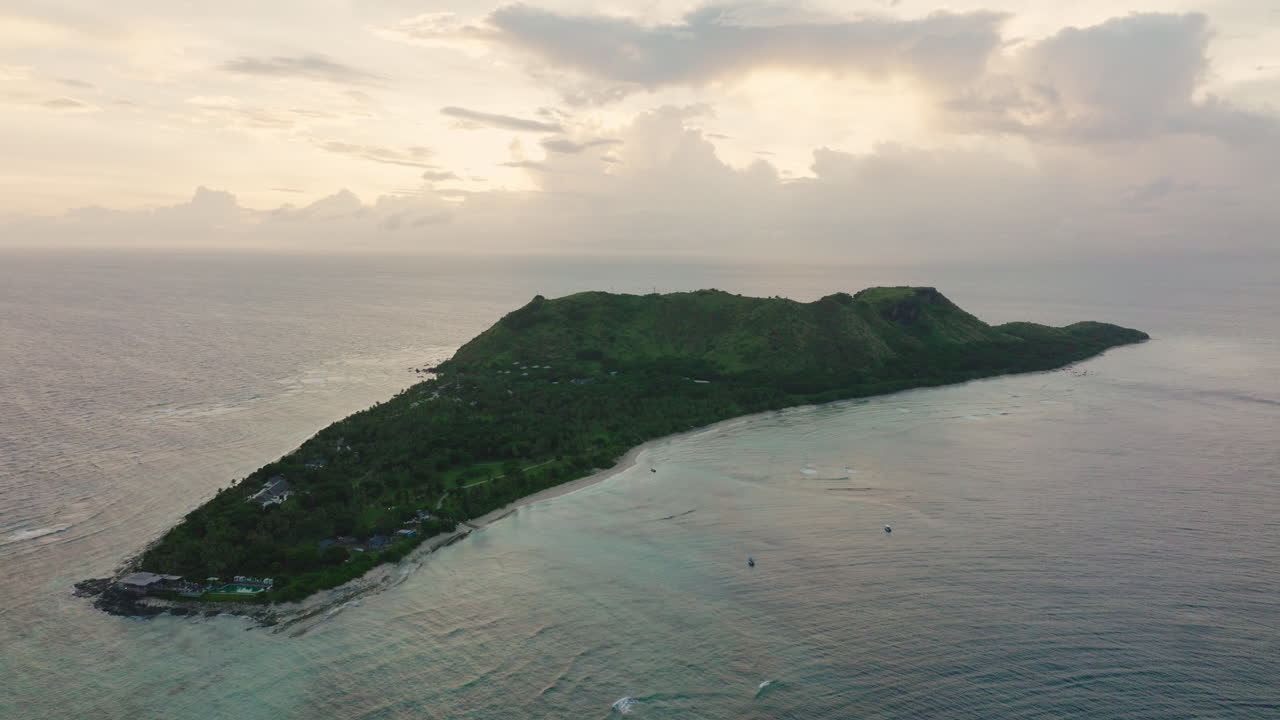 Wide aerial of long tropical island with forest ridge and ocean horizon