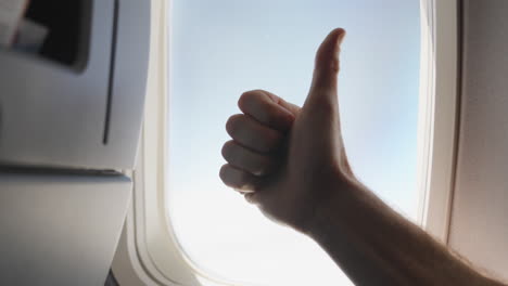 window seat on airplane hand doing a thumbs up on window background on plane