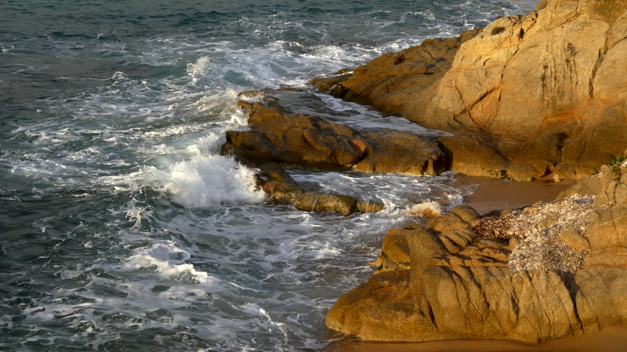 Onde del mare che si infrangono sugli scogli della costa.