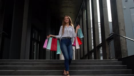 Smiling-girl-walking-from-centre-mall-with-shopping-bags,-happy-with-low-prices-on-Black-Friday