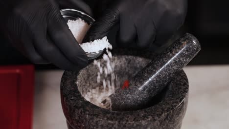 chef añadiendo sal a un mortero y pestillo