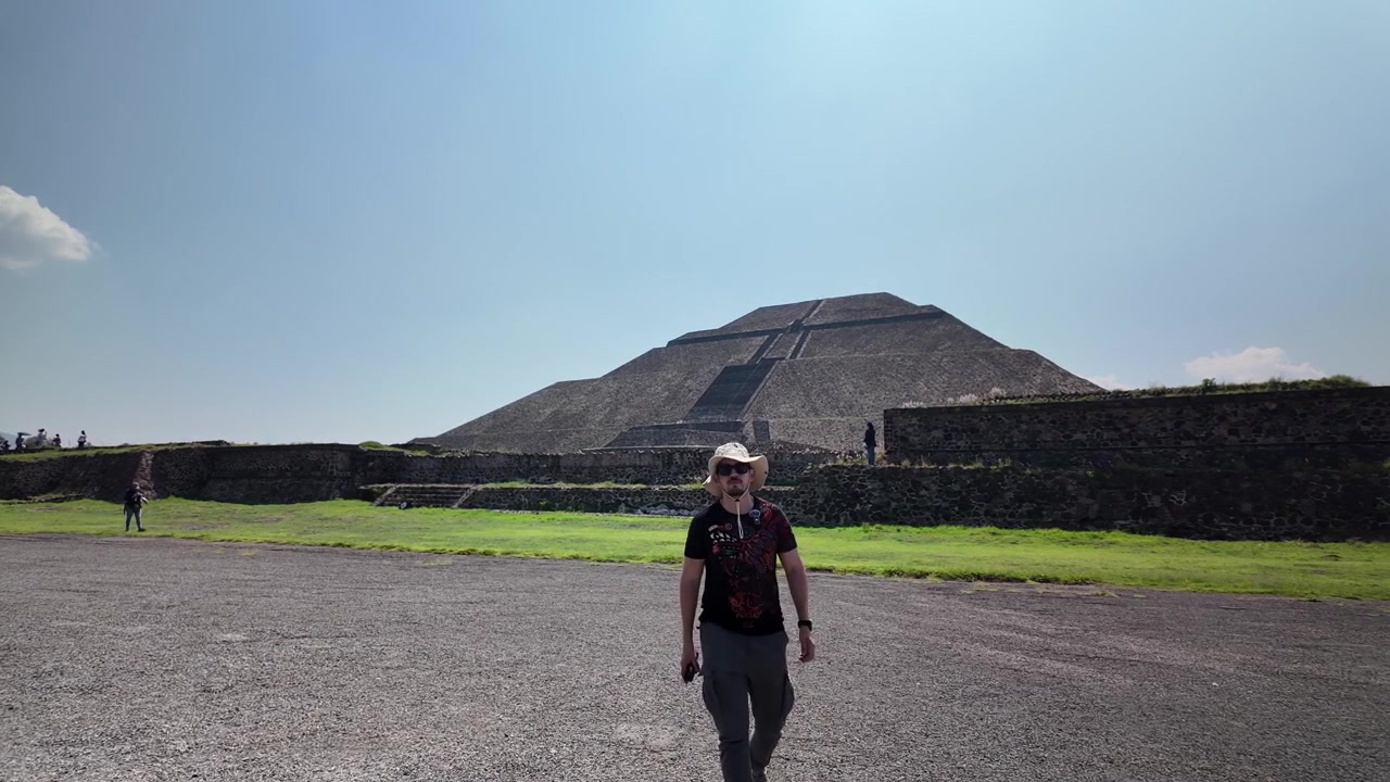 Viaggiatore che cammina verso la Piramide del Sole nel sito archeologico di Teotihuacan, sotto un cielo azzurro e limpido nel Messico centrale.