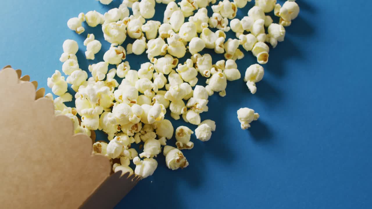 Video of close up of box of popcorn on blue background