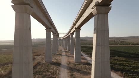 slow flight between the tall pillars of a train bridge at sunset in israel