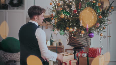 young man hanging bauble on christmas tree at home