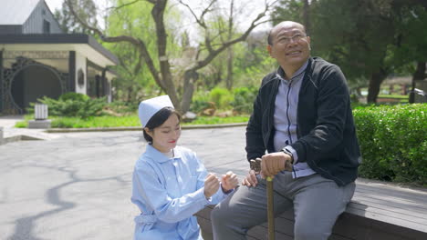 nurse assisting an elderly man with a walking stick outdoors