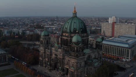 Elevated-view-of-church-with-large-green-dome.-Berlin-cathedral-at-dusk.-Large-city-in-background.-Berlin,-Germany