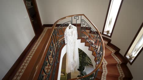 wedding dress hanging in elegant interior with spiral staircase