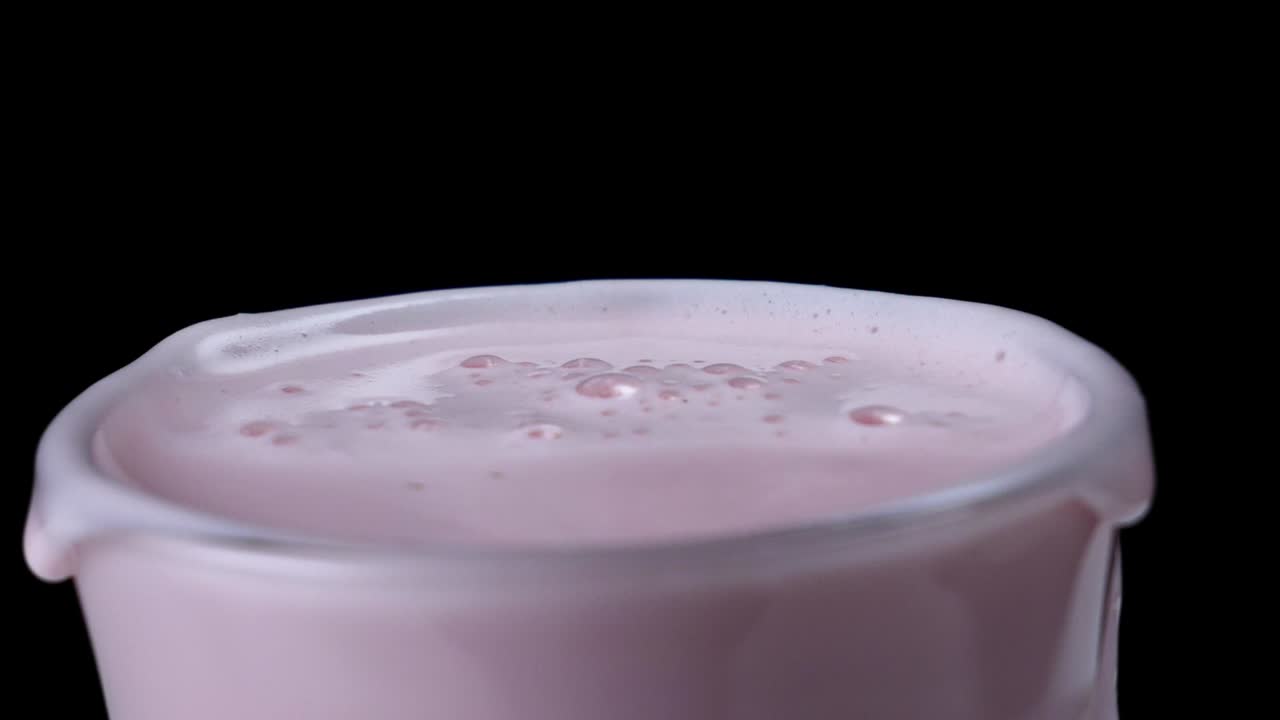 Primo piano di un frullato rosa spumoso in un bicchiere