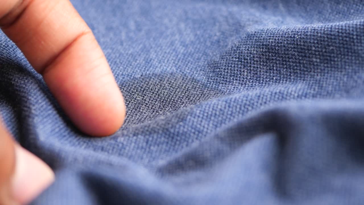 Close-up of a hand touching blue fabric