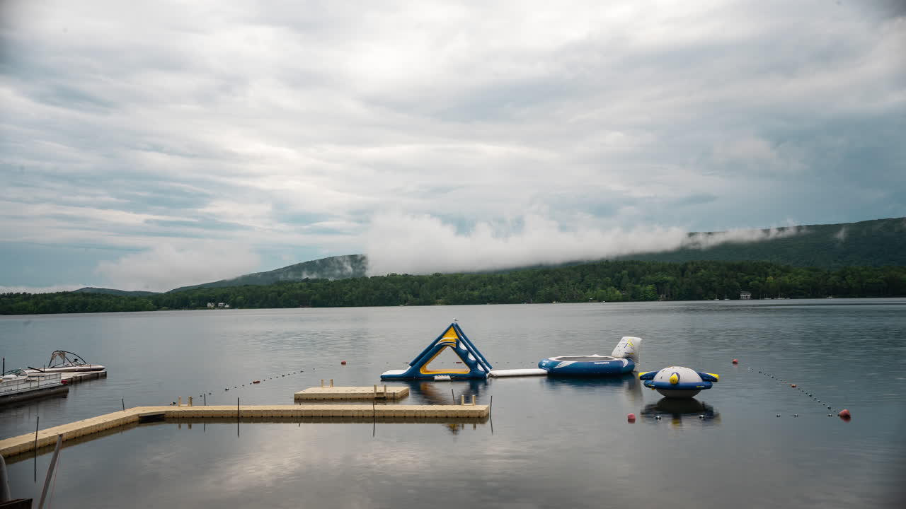 Lake with Inflatable Water Toys and Cloudy Mountain Background