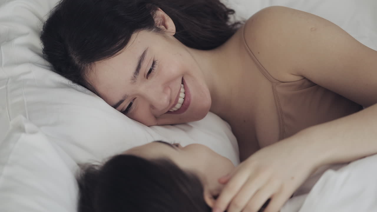 Two women smiling in bed together