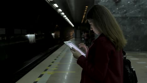 mujer usando una tableta en una estación de metro oscura