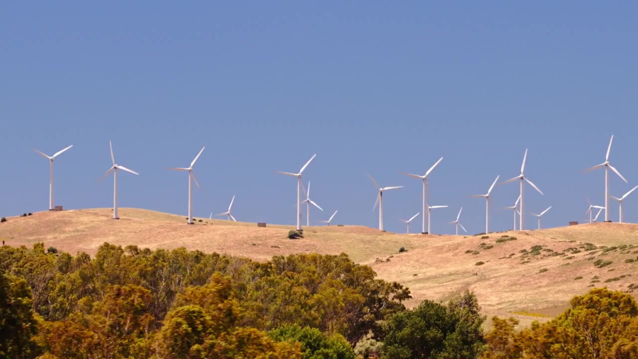 Filmagem cinematográfica de drone de um grande parque eólico com turbinas gerando eletricidade limpa e renovável em uma paisagem rural. Infraestrutura de energia sustentável apoiando a descarbonização e metas climáticas