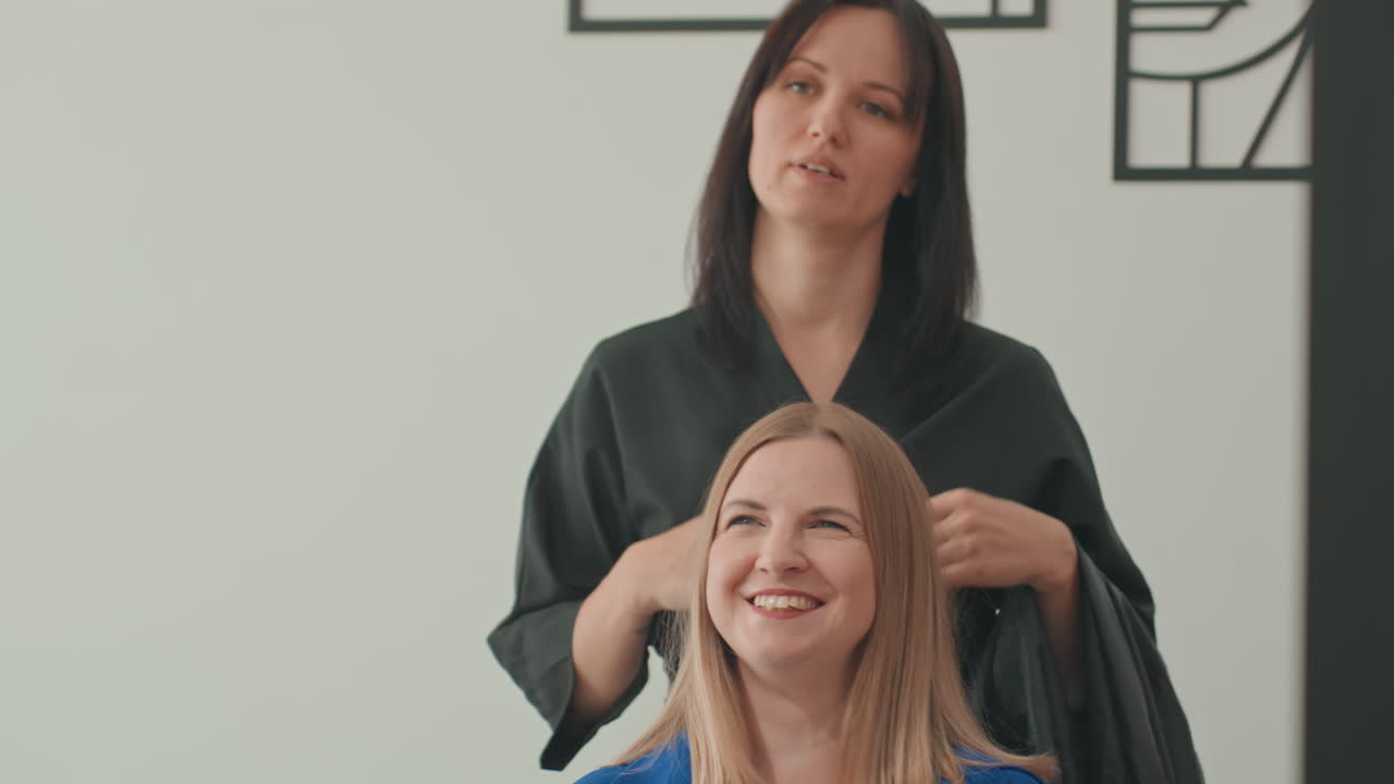 Peluquero examinando el cabello rubio de una clienta en un salón, consulta delicada y evaluación del largo con un peluquero actuando como asesor y técnico capilar, peinando y preparando la capa, enfoque cercano en las hebras