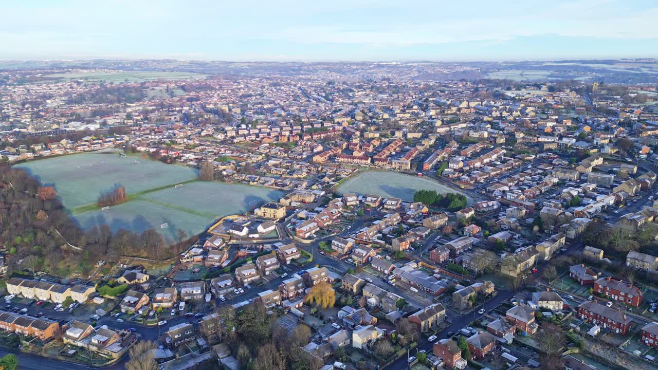 영국 요크셔주 듀즈베리 무어와 헤크몬드와이크의 서리 덮인 도시 마을의 겨울 공중 영상으로 혼잡한 도로 교통과 붉은 벽돌집을 보여줍니다.