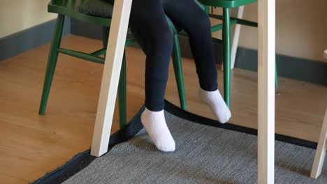 close-up of a child's legs hanging off a chair