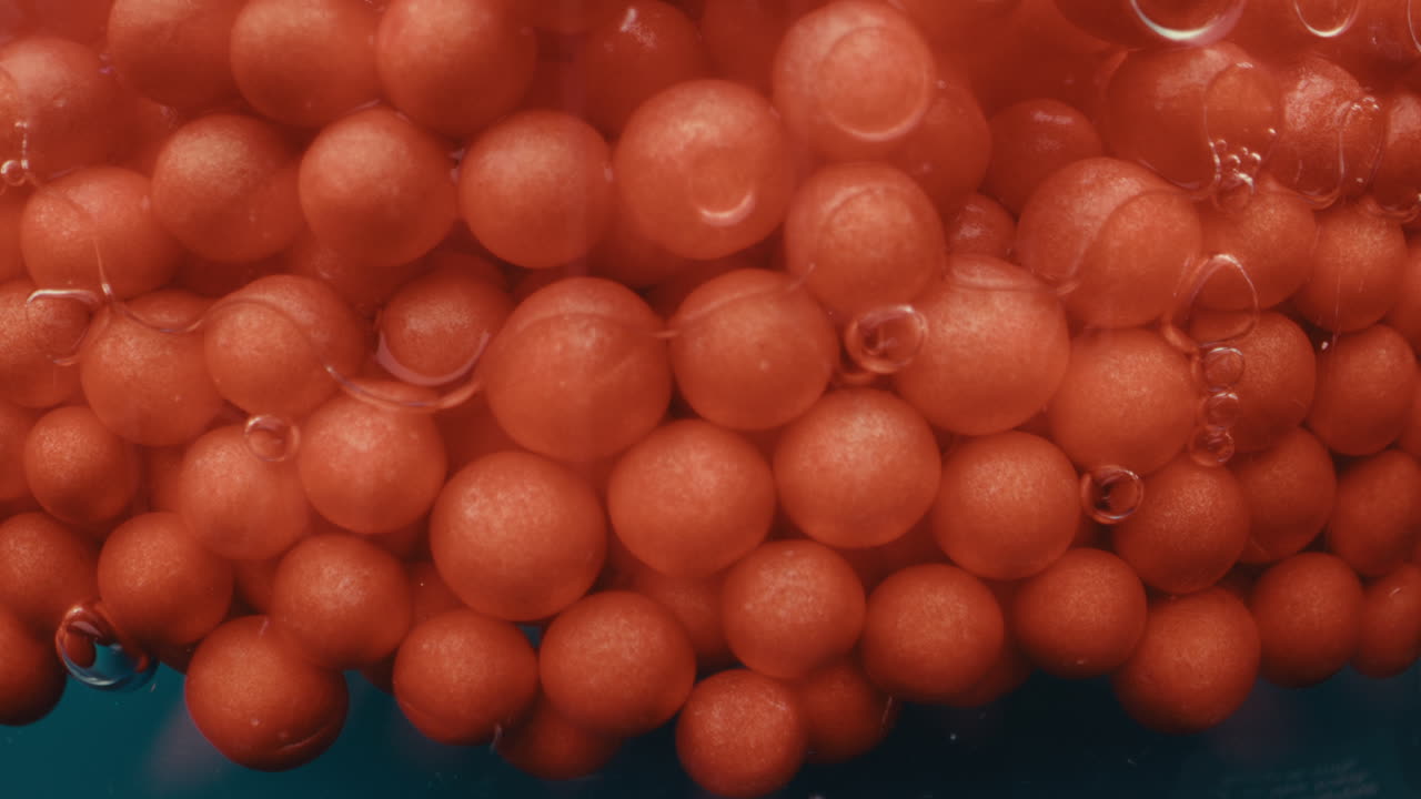 Close-up view of red spheres in liquid with bubbles