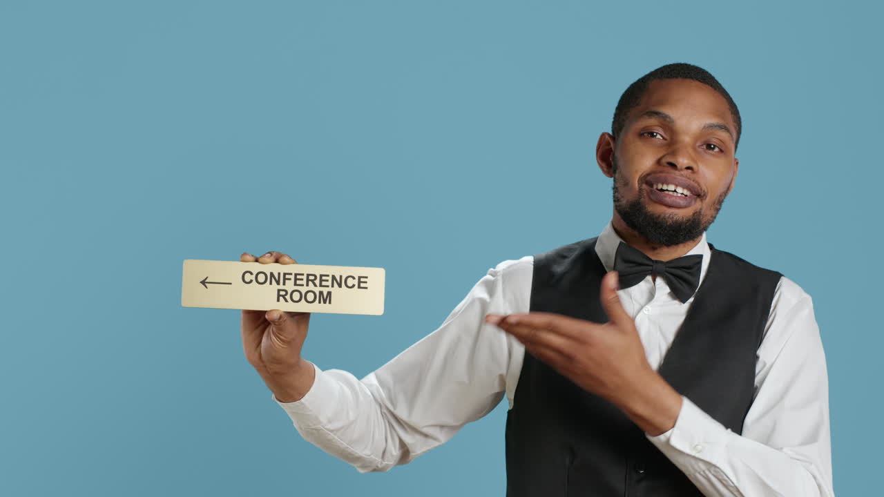 Hospitality industry personnel showing wall sign pointer to the conference room