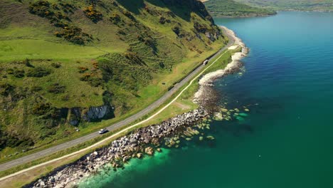 left-to-right travelling aerial video of the causeway coastal route in county antrim, northern ireland, uk, on a bright and sunny day. cars pass below. filmed in 4k, 60fps and with rec709 color.