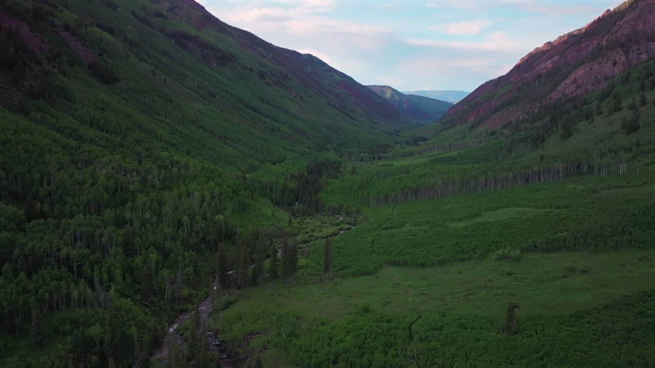 Maroon Bells Wilderness valley Maroon Creek Elk Range Rocky Mountains Colorado aerial drone North Maroon Pyramid Peak sunset spring summer blue sky clouds Aspen Snowmass White River Forest forward