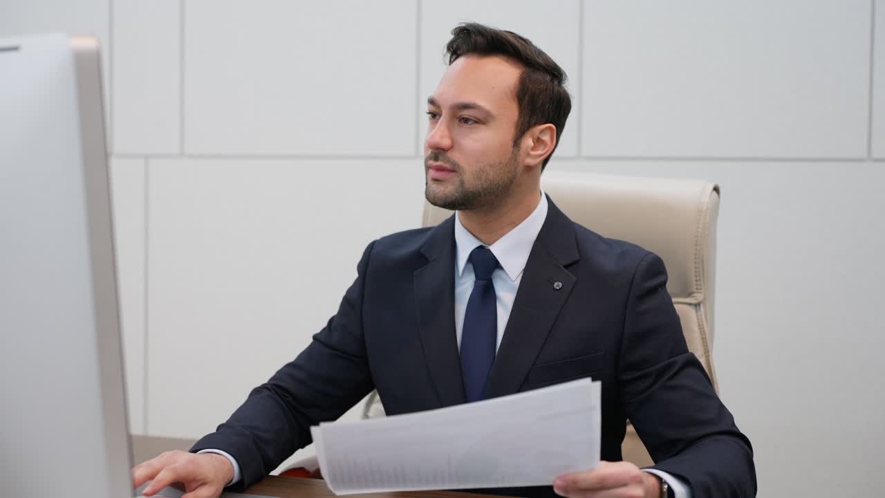 Executive or Businessman reviews paper documents, checking computer display, nodes with positivity and smile