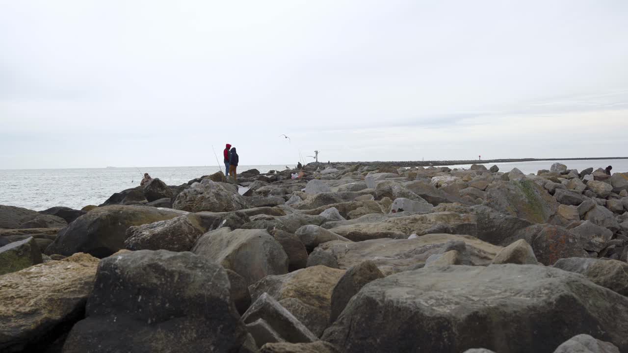해변 부두에서 낚시하는 사람들