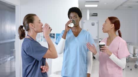 diverse female doctors talking and drinking coffee at hospital, slow motion