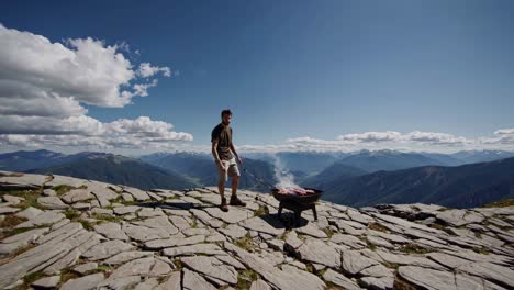 man grilling meat on mountaintop