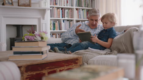 grandfather showing little boy how to use tablet computer teaching curious grandson modern technology intelligent child learning mobile device sitting with grandpa on sofa 4k